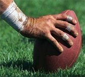 A hand on a football about to be hiked