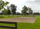 A volleyball court of sand in a green park