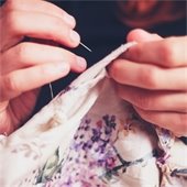 Hands sewing with a needle and thread