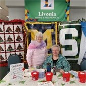 Two women standing in front of quilts being raffled off