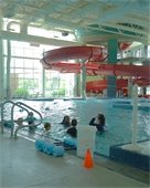 A swim class in a recreation pool with a slide in the background