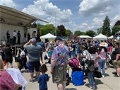 A crowd gathered watching police officers, firefighters, and mascots on stage.