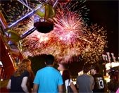 Fireworks over a Ferris wheel and park rides