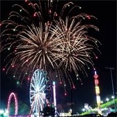 Fireworks over a Ferris wheel and park rides