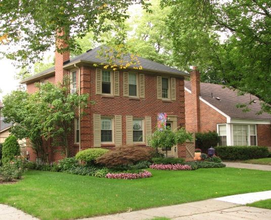 A Two Story House with Brightly Colored Flowers in the Front Lawn